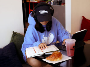 Kudo customer studying with a croissant and iced drink